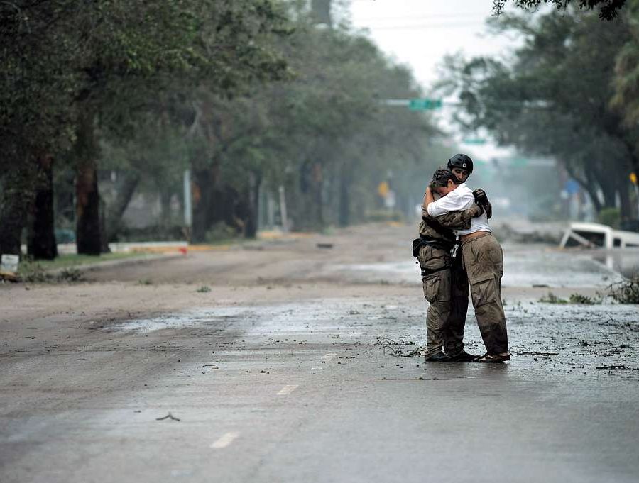 Two people embracing on an empty street after a hurricane.