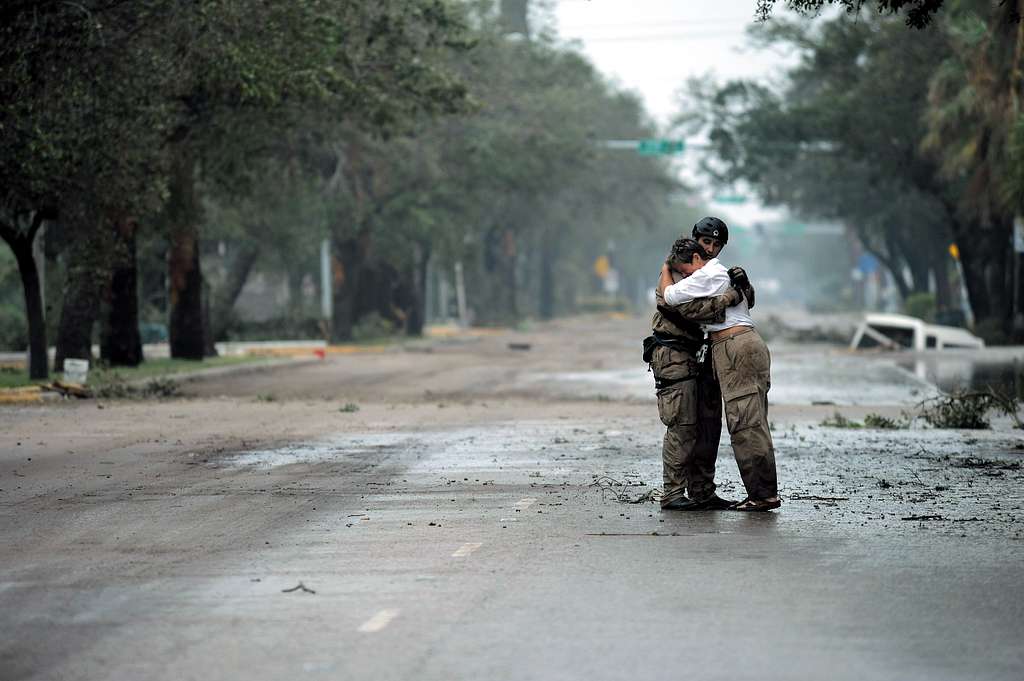 Two people embracing on an empty street after a hurricane.