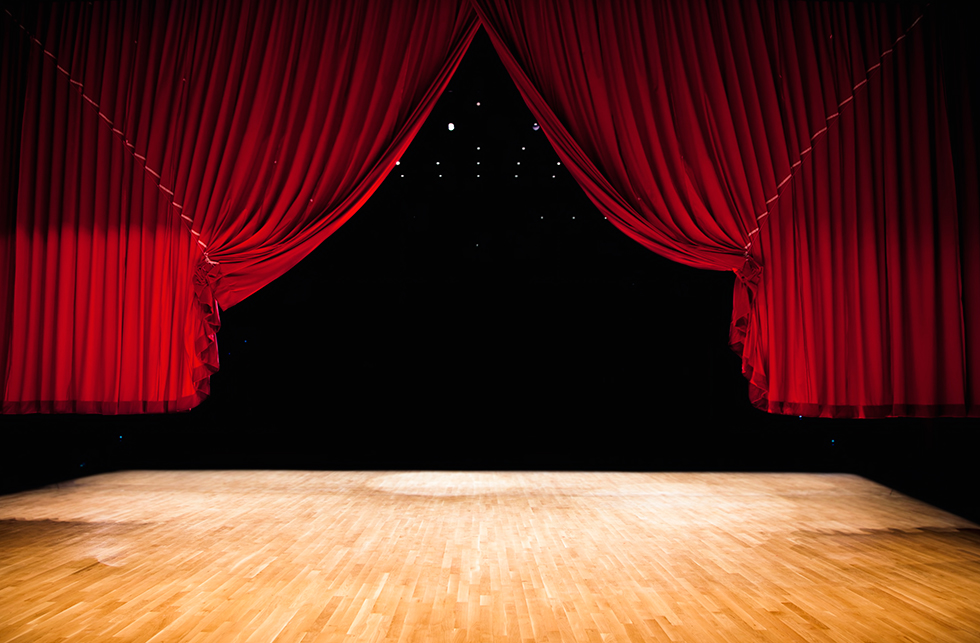 A red stage curtain pulled back.