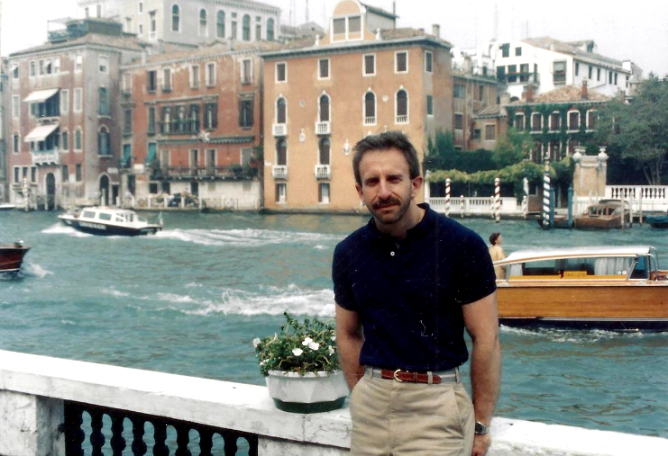 Bruce Dresner, 1987, on the terrace of the Peggy Guggenheim Museum in Venice with the canal in the background, with buildings lining the water and boats passing by. Photo courtesy of Daniel Cotlowitz