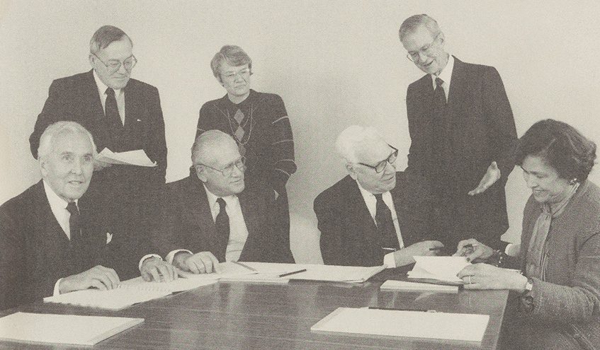 A team gathers at a table filled with papers. John Madden (upper left) at a Distribution Committee meeting with (back row) Karen Metcalf, a Trust vice president; Herbert West, The Trust’s president; and (front row) Frank Detweiler, Arthur Altschul, William Parsons, and Barbara Scott Preiskel.