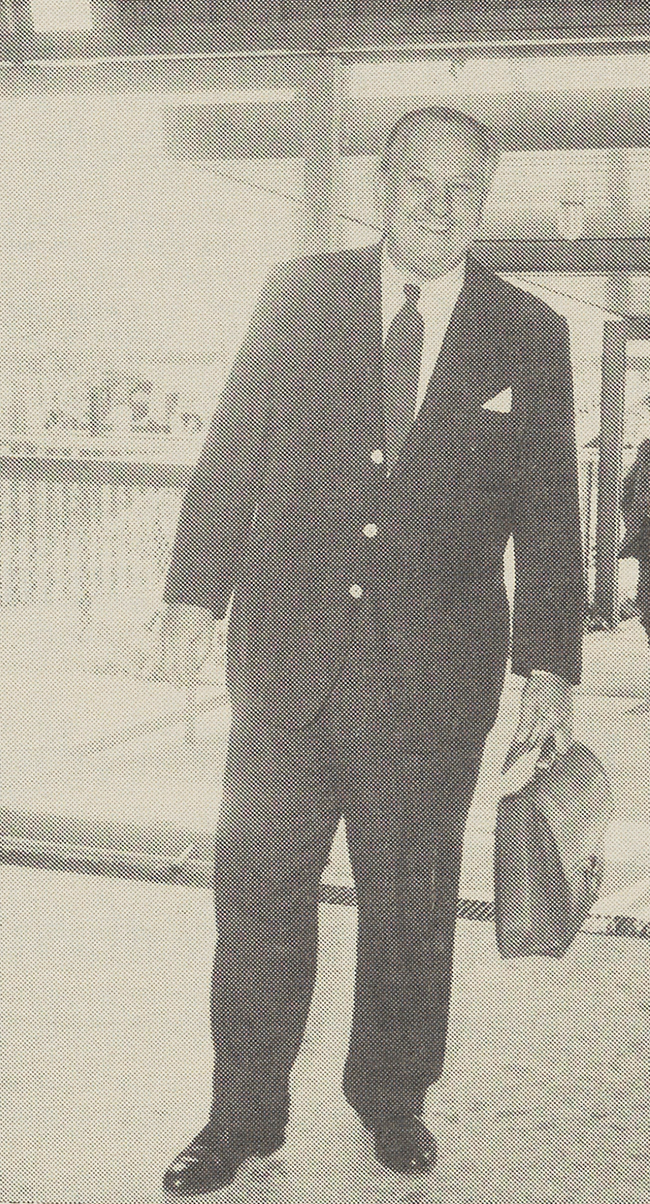 Henry Reichhold on a business trip to Mexico. He is smiling in a suit, carrying a briefcase.