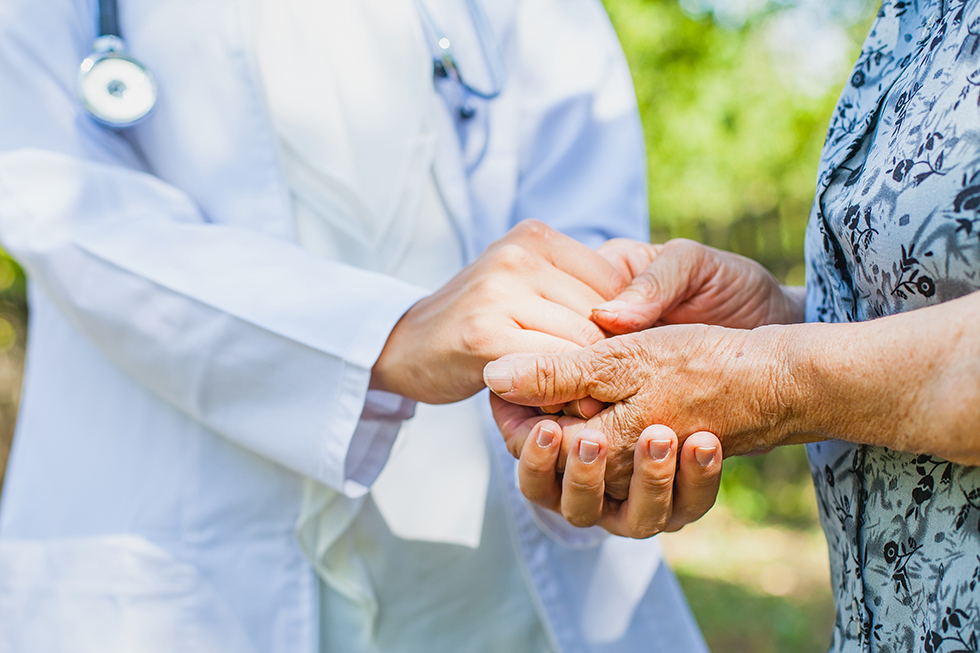 Close up medical doctor holding senior woman's hands.