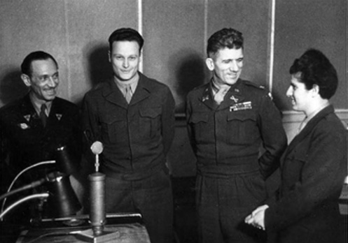A group stands together. RIAS’s original leadership meet with Brigadier General Frank L. Howley. From left: Program Chief Harry Frohman Political Chief Gustav Mathieu, General Howley, and Chief Ruth Norden. Photo credit: From the book, Cold War on the Airwaves: The Radio Propaganda War against East Germany by Nicholas J Schlosser on Google Books.