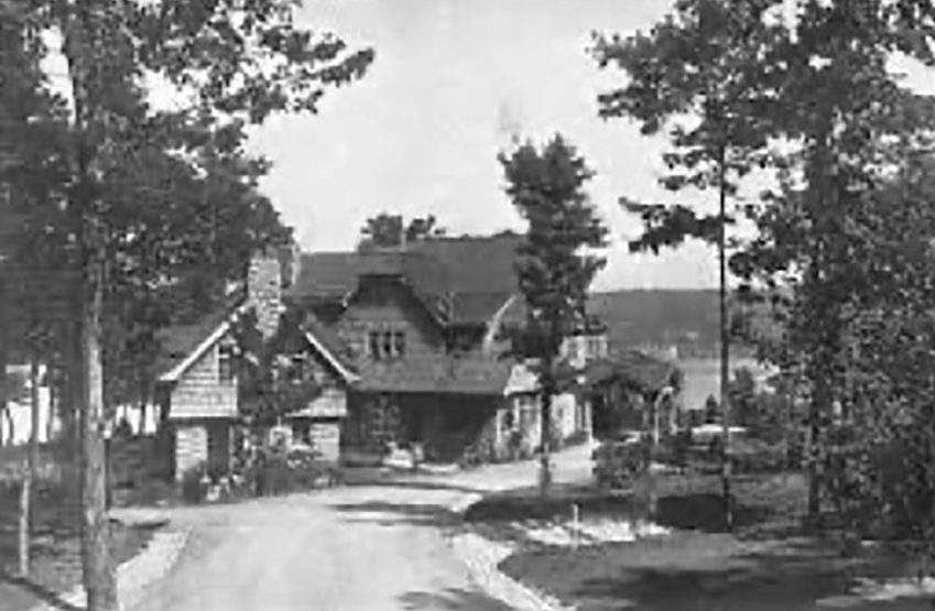 John Lennon’s house in Cold Spring Harbor. A house sits at the end of the driveway surrounded by lush trees. Photo Credit: Facebook