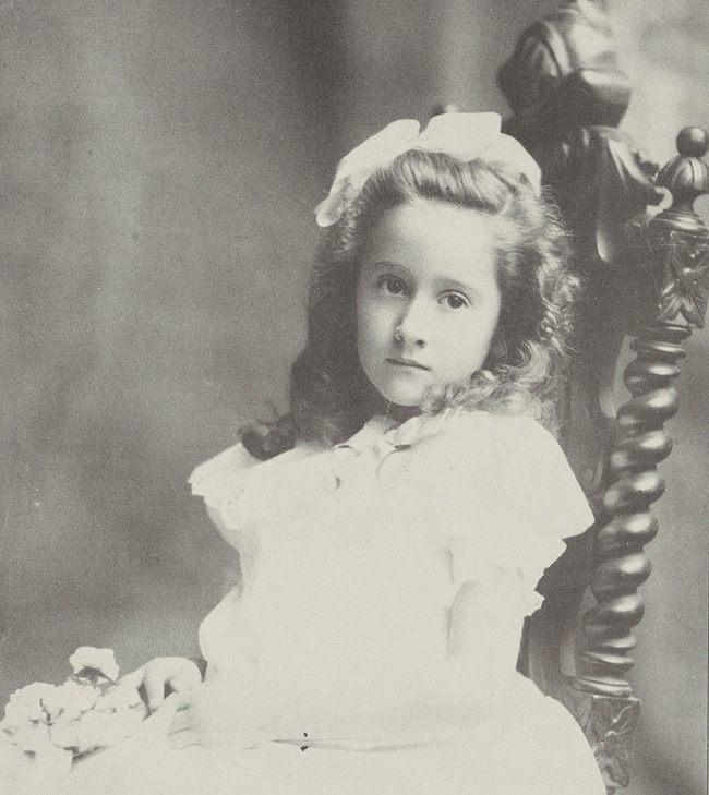 Portrait of young Florence Tobey sitting in a chair with a bow in her hair.