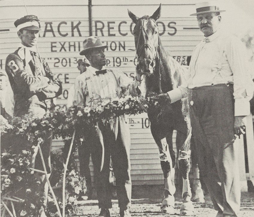 Three gentleman are standing with a horse. Thomas W. Murphy, left, has just driven a former plowhorse named R.T.C. to victory.