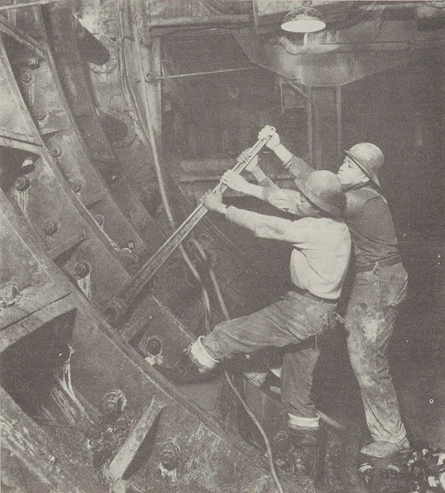 Two men standing side by side tightening bolts in cast iron lining in Queens Midtown Tunnel, February 1939. (Photo courtesy of Triboro Bridge and Tunnel Authority.)