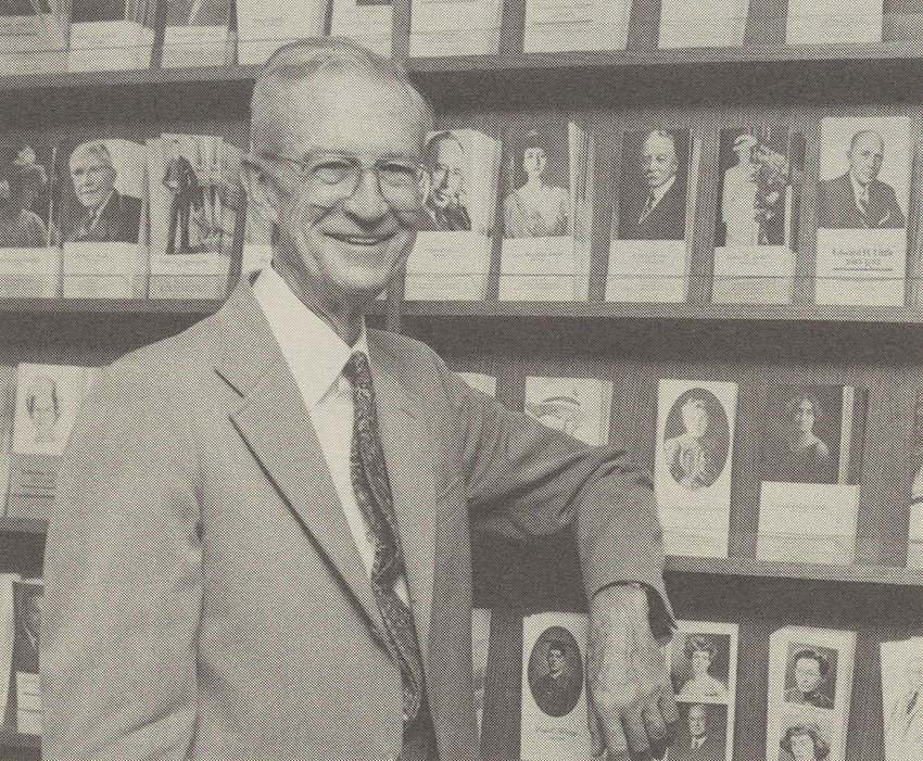Herbert in early 1989 standing in front of a wall with shelves displaying donor biographical sketches, each representing a fund in The Trust.