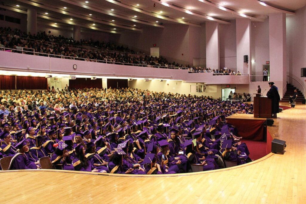 An auditorium filled with graduating students from Silberman School of Social Work, wearing purple caps and gowns.