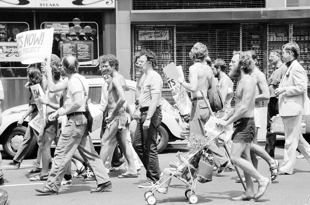 A group of men walking down the street holding signs in support of LGBTQ+ rights in 1976.