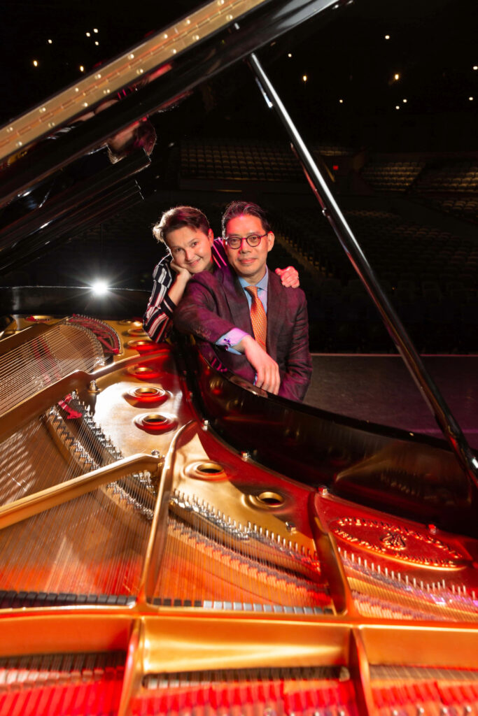A couple stands near a grand piano