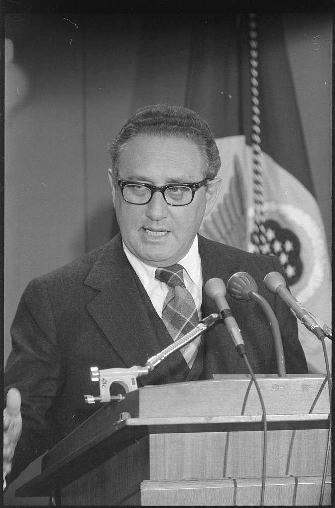 Henry Kissinger speaking at a podium.
