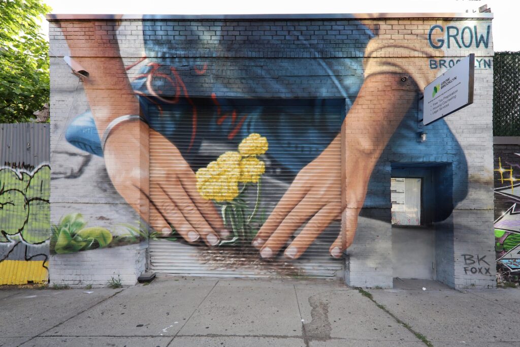 Mural art of a person planting flowers in sidewalk cracks.