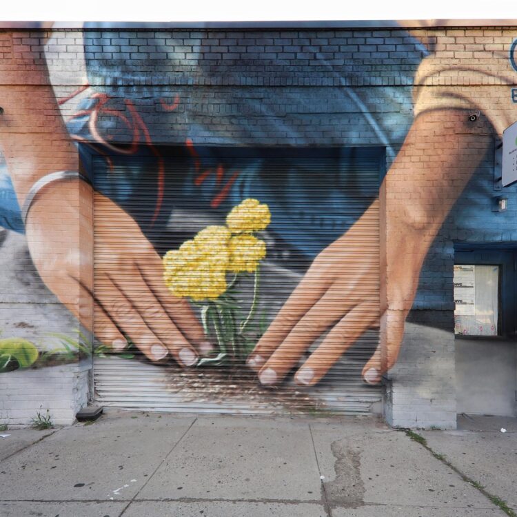 Mural art of a person planting flowers in sidewalk cracks.