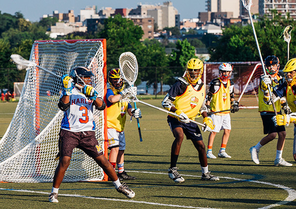Young athletes play lacrosse on a field.  