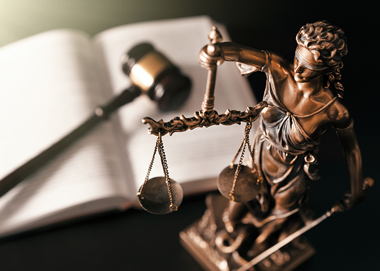 A statue of Lady Justice and an open book with a gavel.