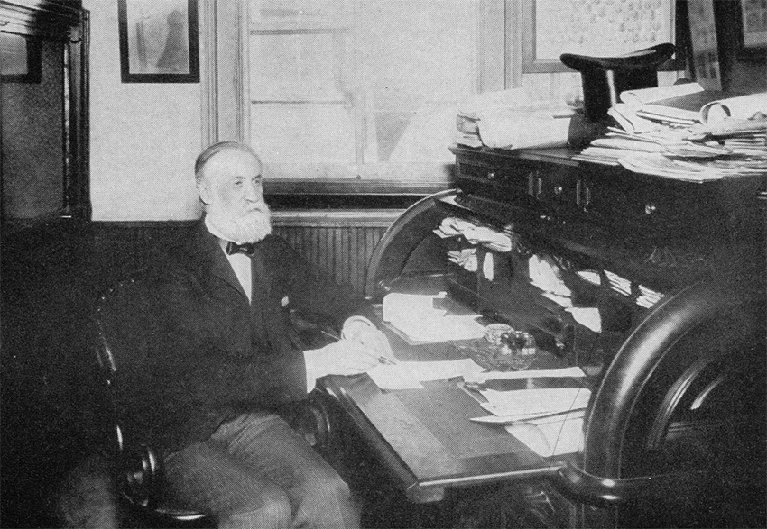 James Talcott sitting at a desk full of papers in 1899.