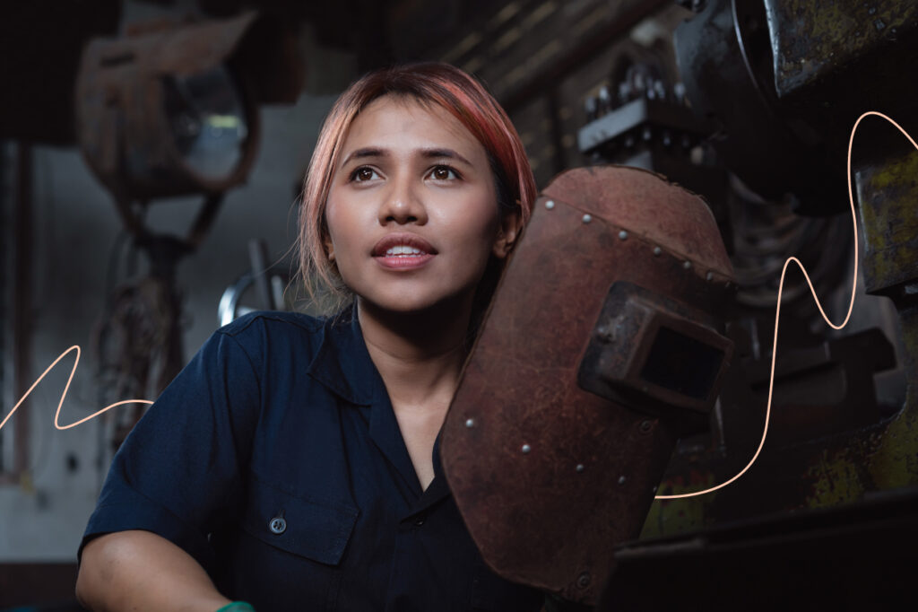 A young woman who has removed her welder’s mask.