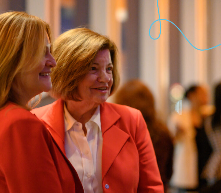 Two women mingle at an event. 