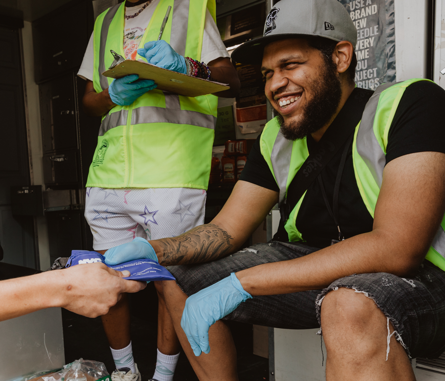 An OnPoint staff member hands a kit to someone off screen at a supervised injection site.