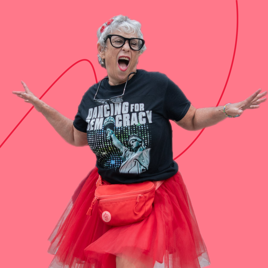 Older woman in pink skirt dances with a Dancing for Democracy shirt on