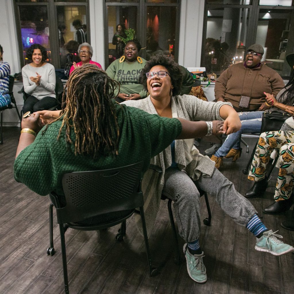 Adults seated in a circle with joyous expressions