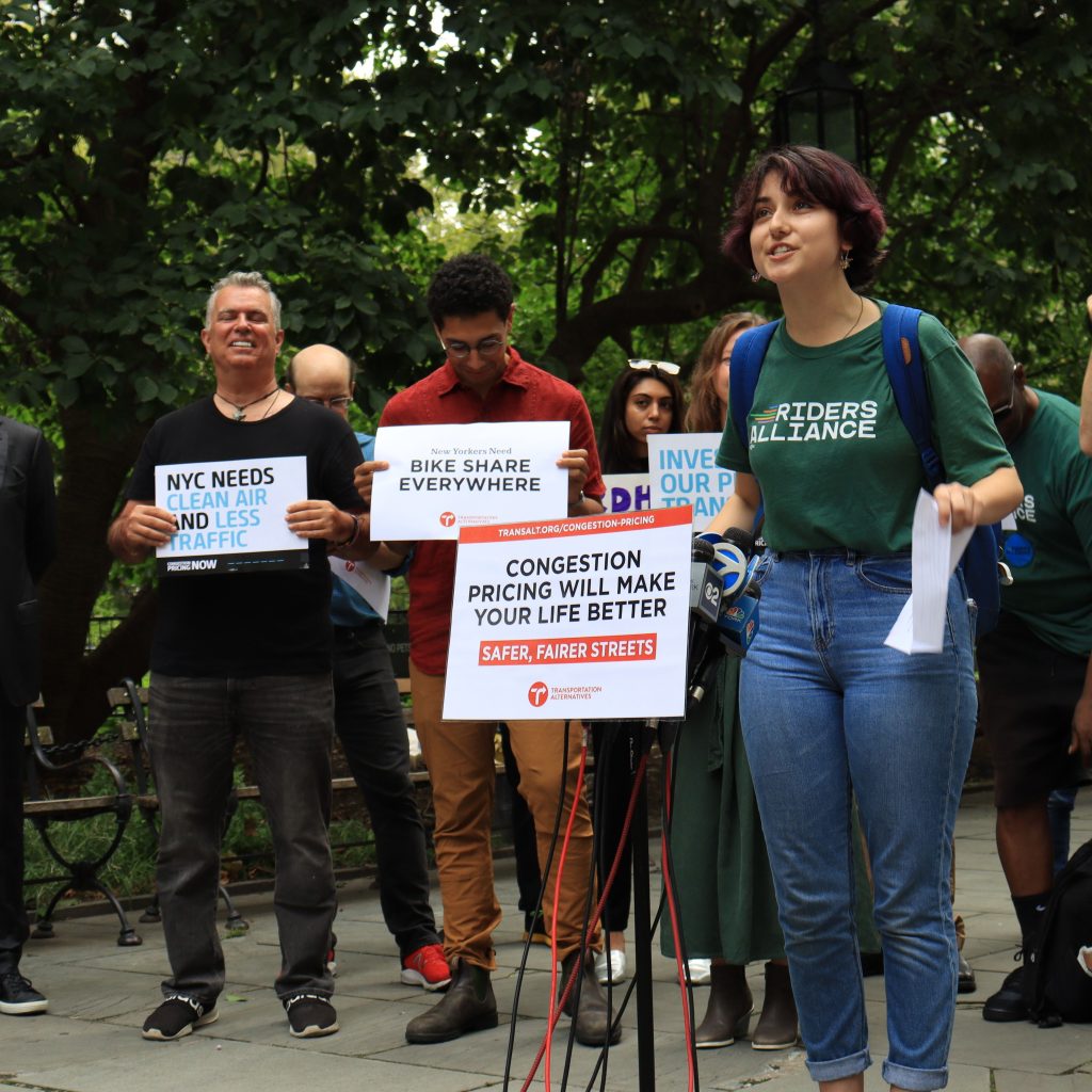 Photo of people holding signs about transit initiatives in NYC.