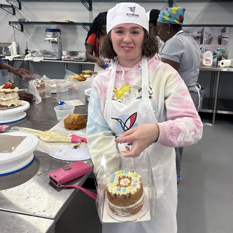 A student at Kindred Bakery displaying their decorated cake